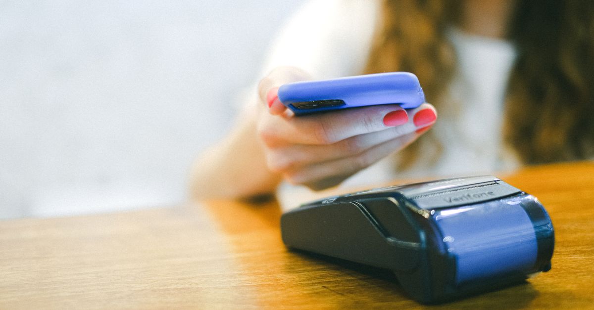 Close-up of a woman making a contactless payment using a smartphone over a card reader